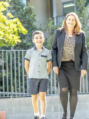 Student and teacher walking together outdoors near a school building.